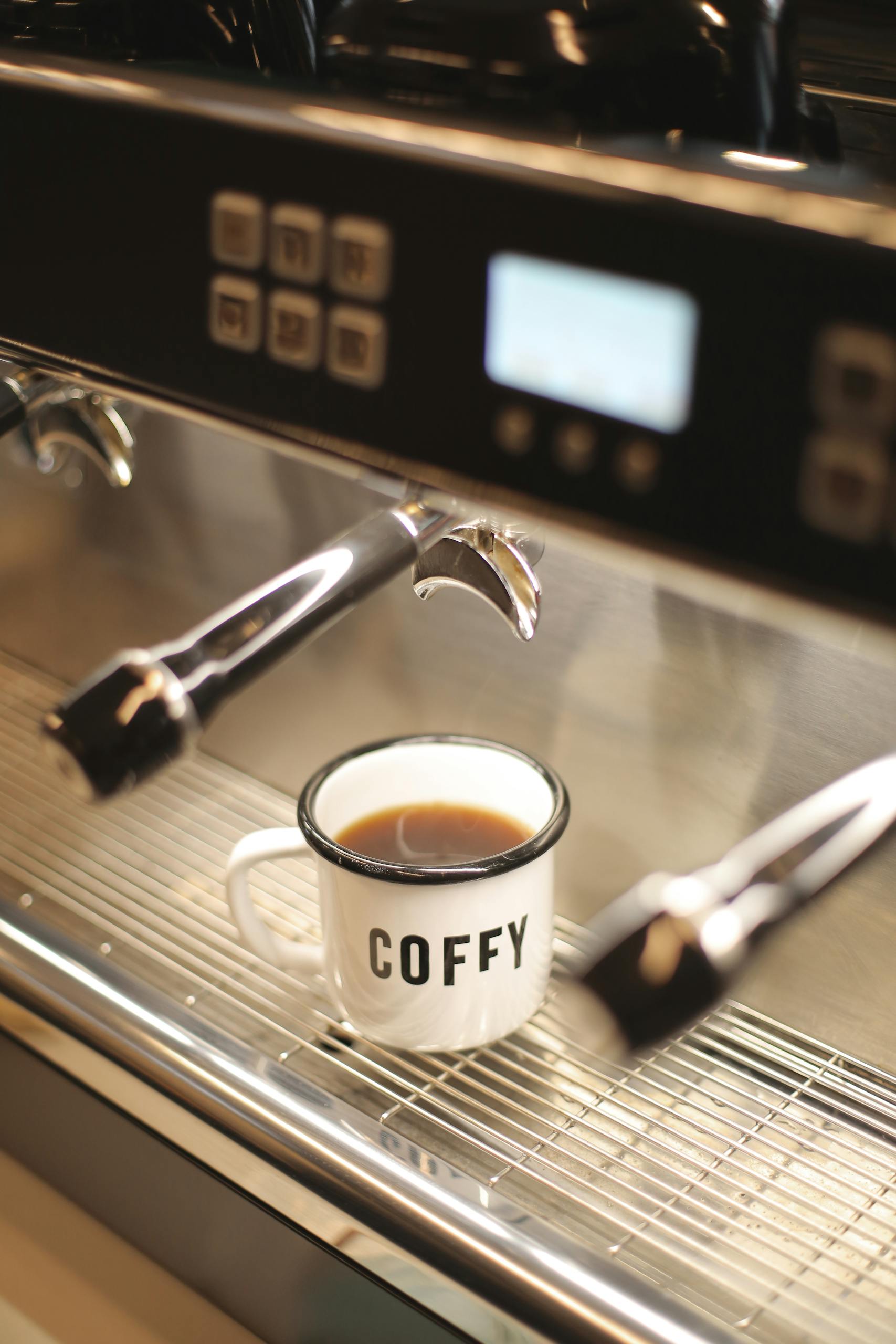 Vintage coffee cup labeled 'Coffy' in a modern espresso machine setting.